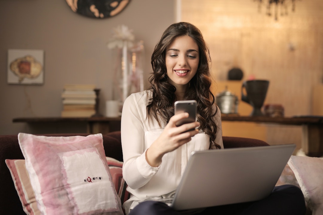 Image of a Woman smiling at her phone - photo by Andrea Piaquadio - Pexels