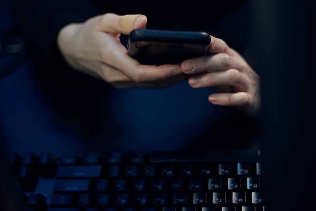 Dark mode - Photo of a person with a black phone and a black keyboard