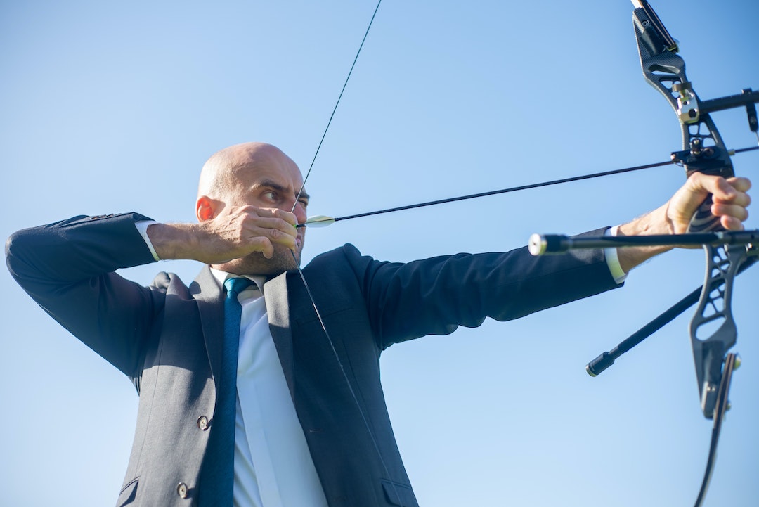 Man in suit practicing archery - Photo by Kampus Production on Pexels
