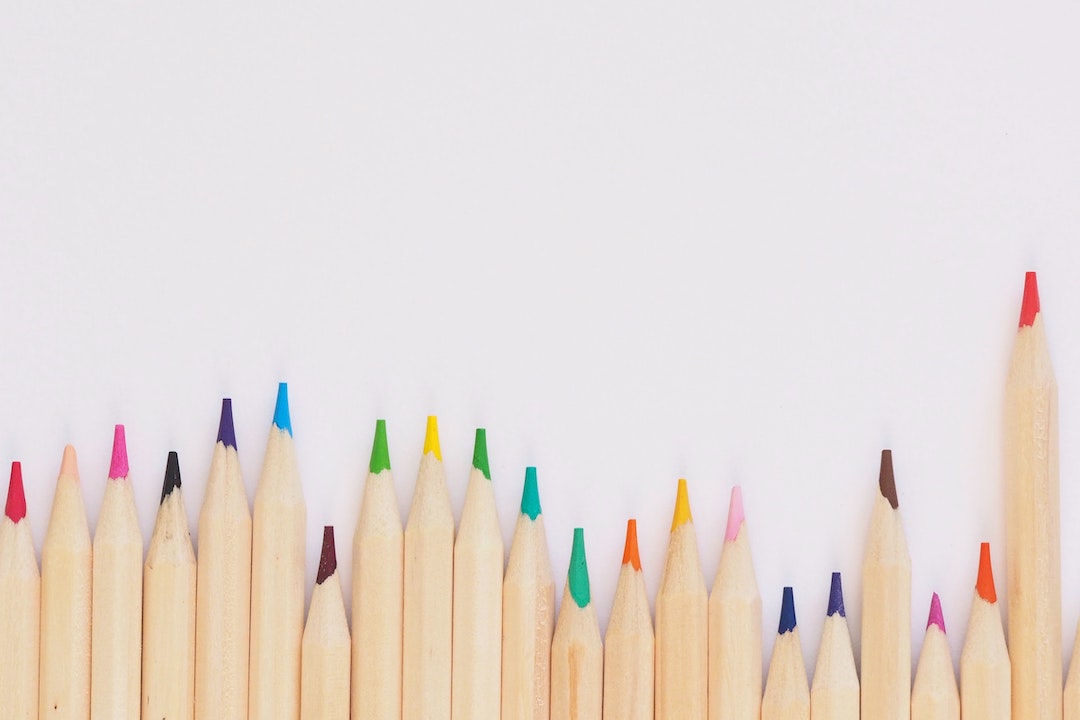 A row of color pencils on a white background - Photo by Jess Bailey Designs - Pexels
